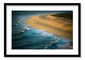 The surf beach in Nazare, Portugal, with the calm Atlantic stretching to the horizon. Soft waves lap the shore, creating a serene coastal view.