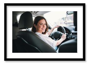 Young woman smiling while driving a car on a sunny day, enjoying a weekend getaway