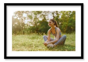 Young athletic woman stretching outdoors in a green park, illustrating healthy lifestyle, fitness, and outdoor exercise in summer