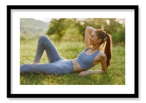 Young athletic woman in blue sportswear enjoying a sunny day on the grass, promoting healthy lifestyle and fitness