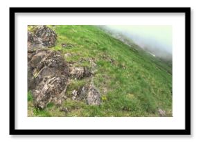 Panoramic view of a mountainside with rock formations and a cave entrance