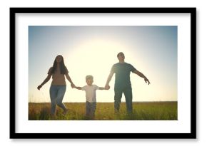 family walking together. outside people and family concept. happy family of three walking through a large field at beautiful sunset, mom and dad holding their son hands lifestyle