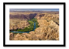 Impressive panorama of Charyn Canyon in Kazakhstan, featuring a meandering river and unique rock formations under a clear blue sky