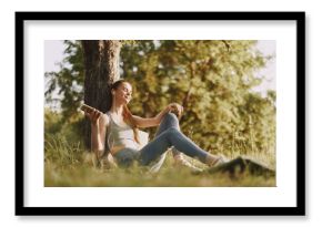 Young woman enjoying music outdoors in a serene park, wearing casual sportswear, exuding happiness in a sunlit natural setting