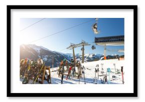 Sunny winter day on alpine slope with skis and snowboards resting near gondola station. Bright sunlight, blue sky, and mountain panorama create atmosphere of adventure, freedom, and relaxation