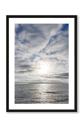 A calm ocean with a bright sun shining on the water