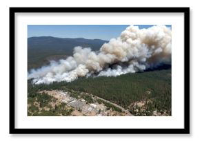 Large wildfire releases thick smoke over forested area near community in northern California during summer months