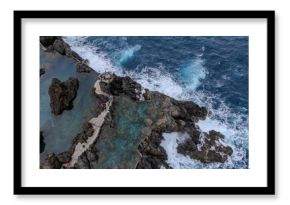 Aerial view of natural lava pools and coastal village in Porto Moniz, Madeira, surrounded by dramatic cliffs and Atlantic waves. 