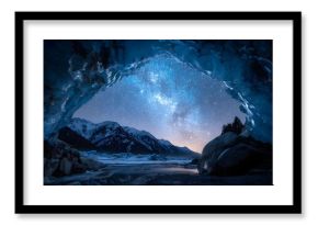 Starry night sky with the Milky Way visible, framed by an icy cave arch, overlooking snow‑capped mountains and a frozen lake. Concept Milky Way night sky, icy cave arch, snow-capped mountains
