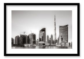 Monochrome city skyline with tall skyscrapers reflecting on calm water under a cloudy sky, Dubai Marina bay UAE
