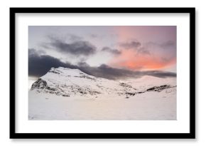 View of snow-capped mountain peaks under a bright sunrise sky. The white snow contrasts beautifully with the clear sky. Beautiful landscape for a natural or winter background or wallpaper