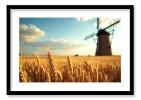 Golden wheat field with a traditional windmill in the background under a partly cloudy sky during sunset