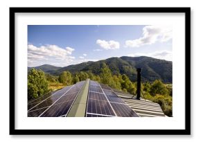 Solar panels installed on a rooftop with a stunning view of lush green mountains under a bright blue sky. A perfect blend of sustainable energy and natural beauty