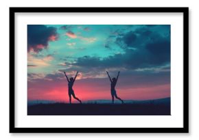 Two young women practicing yoga at sunset