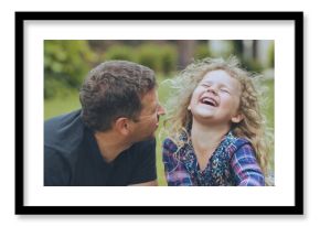 Father laughing together with daughter during sunny park walk, enjoying playful bonding moment with genuine family happiness