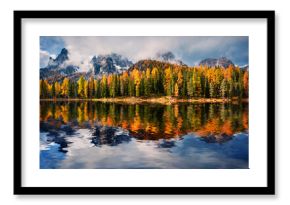 Huge peaks and colorful larch trees reflected in the calm waters of Antorno lake. Dramatic autumn scene of Dolomite Alps, National Park Tre Cime di Lavaredo, Italy. 