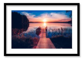 Sunset on a lake. Wooden pier with fishing boat at sunset in Finland