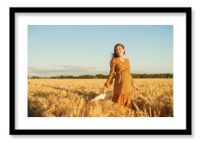 Pregnant woman in the rays of the sunset. Beautiful young girl is walking in the field expecting the birth of a child. Motherhood, pregnancy and happiness concept.