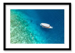 Aerial view sailing boat next to reef. Bird eye view, water sport theme. Snorkel excursion, recreational dive with tourist. Luxury water sport outdoors activity in Maldives. Exotic travel landscape