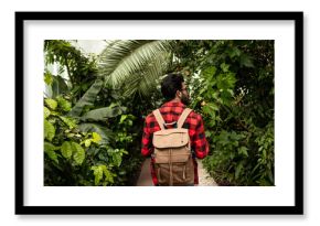 Dark-haired hindu man with backpack walking in botanical garden