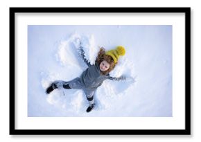Winter fun. Child making a snow angel in winter day. Happy kid lying in the snow. Kid angel in snow. Winter kids with snowy angel wings. Smiling child on a winter day. Child in the snow lake angel.