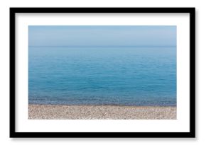 The ocean is calm and clear, with a few rocks on the shore