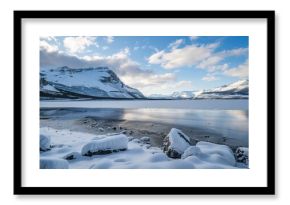 A serene winter lake lies in the midst of snow - covered mountains, with its shoreline frozen. The still water of the lake reflects the majestic peaks, and the white snow adds a touch of purity and tr