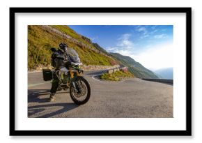 Motorcycle rider riding in Italian Alps during sunrise, dramatic sky. Travel and freedom, outdoor activities