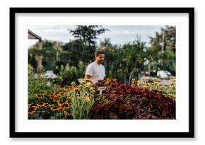 Customer shopping in garden centre, standing behind rows of flowers and plants.