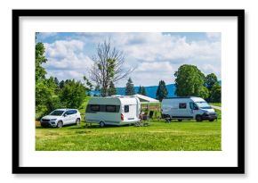 A scenic camping spot with a caravan, car, and camper van on a green meadow beneath a blue sky with fluffy clouds, ideal for travel and outdoor adventure themes.