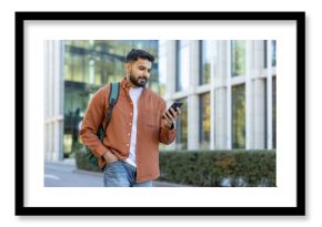 Young man using smartphone on a city street close to modern buildings