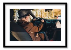 Elderly man drives in autumn sunshine enjoying a leisurely drive in a park surrounded by fall foliage and outdoor beauty