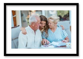 Senior couple showing family photo album to granddaughter.