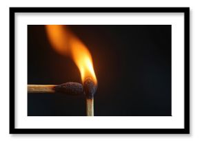 Close up two wooden matches. Burning match ignites another stick, creating bright orange fire flame. Heat energy transfers, showing new light from connection. Dark black background highlights intense