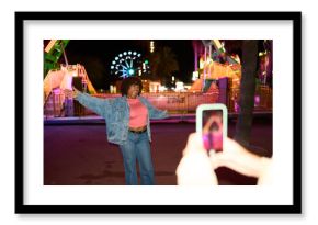 Young woman filming video for social media at night carnival