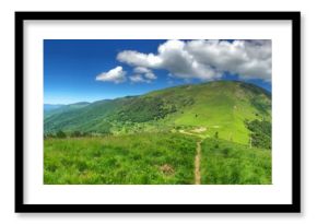 Panoramic view of lush green mountains under vibrant blue skies with clouds
