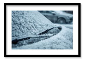 Frozen windshield with snow on a vehicle. Frosted wipers and washer nozzles. Ice-covered automobile surfaces.