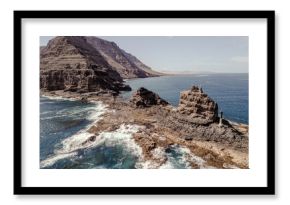 Aerial view of rugged volcanic cliffs and rock formations near Orzola, Lanzarote, surrounded by turquoise Atlantic waters.   
