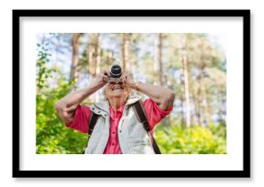 Elderly woman photographing nature during forest walk.
