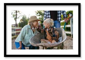 Grandmother playing with grandson in a wheelbarrow on a family farm.