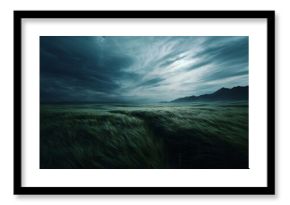 Dramatic stormy sky over a wind swept grassy field with distant mountains