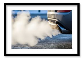 Car exhaust pipe emitting dense white smoke in cold winter air for environmental pollution concept and global warming concerns