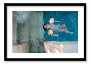 A young child delightfully enjoys floating in a refreshing pool, wearing colorful arm floats