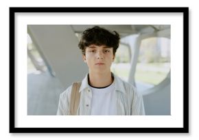 Portrait of serious teen boy wearing casual clothes and beige backpack