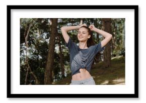 Joyful young woman enjoying nature, smiling and posing playfully in a forest setting Leisure and happiness concept focused on outdoor relaxation