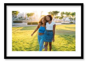 Two young women walking and laughing together in a park