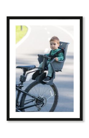 Portrait of Caucasian little boy on bicycle chair. Vertical photo. 