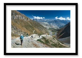 Panoramic view of mountains with group hikers on trail against background of picturesque mountain landscape while trekking around Annapurna in Himalayas, Nepal.