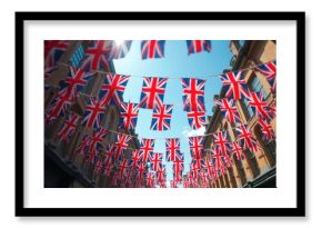 British Union Jack flag garlands decorate London street. UK national colors for celebration, holiday. British flag banners in sky. Royal festival mood.