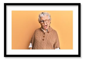 Senior grey-haired woman wearing casual clothes and glasses winking looking at the camera with sexy expression, cheerful and happy face.